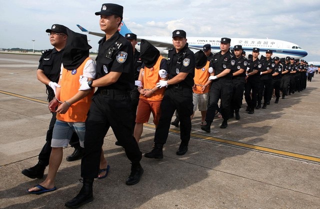 Cảnh sát Trung Quốc áp giải các nghi phạm lừa đảo người Trung Quốc bị Campuchia trục xuất tại sân bay ở tỉnh Hồ Nam hồi tháng 7 (Ảnh: Reuters)