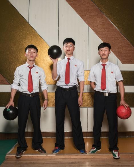 Sinh viên Triều Tiên chơi bowling. Cả 3 đều mặc đồng phục sơ mi trắng, quần đen, đeo cà vạt đỏ và mang huy hiệu trên ngực trái. (Ảnh: Stephan Gladieu)