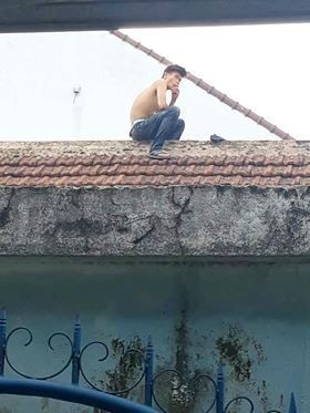 Bắt thanh niên nghi ngáo đá cầm dao cố thủ trên mái nhà dân - 1 Nam thanh niên nghi ngáo đá ngồi trên nóc nhà (ảnh: Minh Đức)