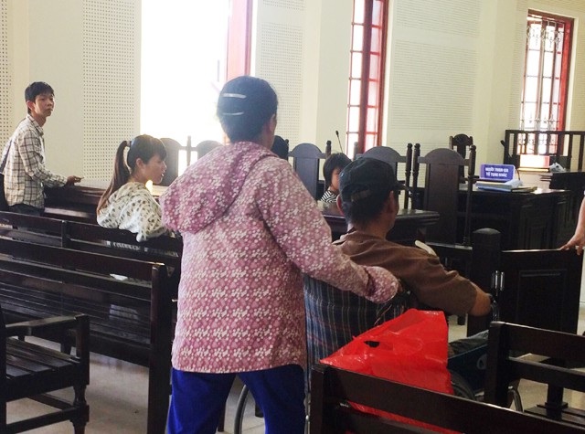 Tâm sự người vợ có chồng ngồi xe lăn “đổ đốn” với cháu bé thiểu năng - 1 Bà Q. đẩy xe lăn đưa chồng vào vị trí bục khai báo dành cho bị cáo. Ông Nguyễn Thanh An - chồng bà bị truy tố xét xử về tội Dâm ô đối với trẻ em