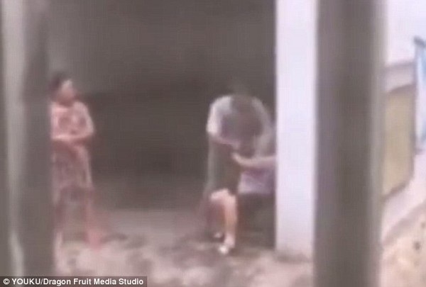 Ông Lượng đang dùng tay để ép mẹ mình phải ăn cỏ trước sự chứng kiến của người vợ