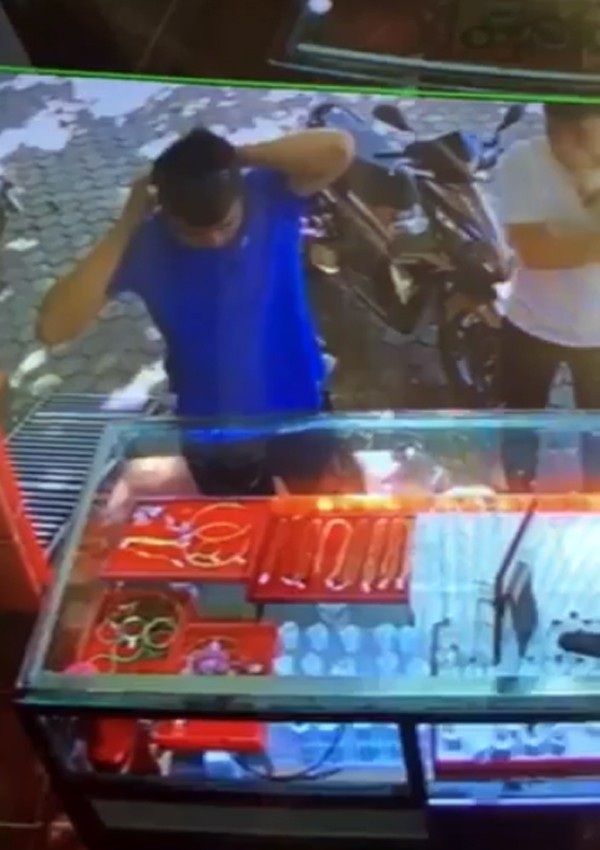 Đối tượng áo xanh mở dây chuyền vàng đeo ở cổ để bán cho tiệm vàng Ngọc Hà (ảnh cắt từ clip)