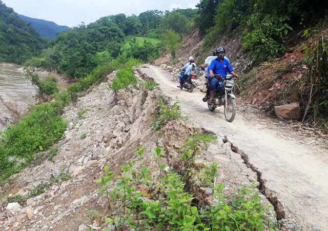 Chênh vênh đi trên đường vành đai biên giới sau bão số 3 - 11 Người dân di chuyển chênh vênh trên con đường đang bị sông bóc đến tim đường