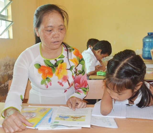 Tấm lòng thương trẻ khuyết tật của cô giáo xứ cù lao - 2 Cô Thúy đang hướng dẫn em Thảo học, viết bài.