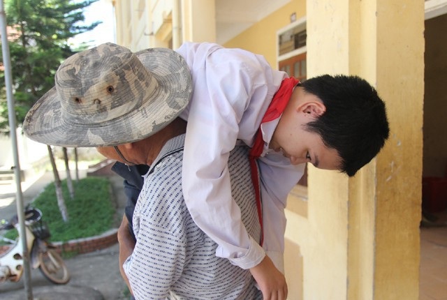 Người cha 10 năm vác con đi học, màu tàu điện cảm hứng từ vỏ thanh long - 3 Càng lớn, hai chị em Sương, Sáng càng yếu dần đi rồi không thể đứng được nữa, đôi chân trở nên mềm nhũn, thõng thượt. Thương cho khát khao tới trường học chữ của con, 10 năm nay ông Nguyễn Văn Sơn đều đặn ngày vác con ra xe chở tới trường học. (Ảnh: Hoàng Lam)