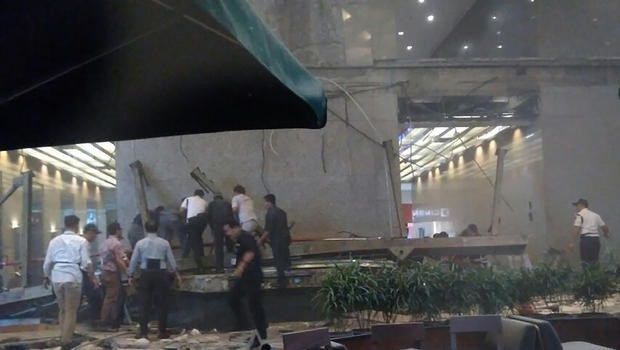 Tầng lửng sàn chứng khoán Jakarta đổ sập, thị trường vẫn giao dịch bình thường - 2 Mọi người chạy trốn khỏi tòa nhà qua một hành lang với đầy các mảnh vụn. (Nguồn: CBS News)