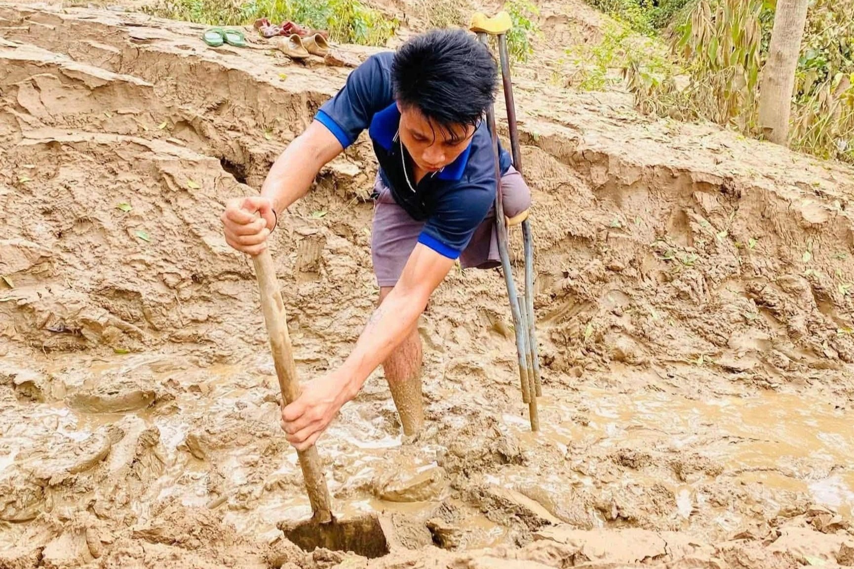 Người đàn ông cụt chân vác xẻng đào bùn giúp hàng xóm sau mưa lũ