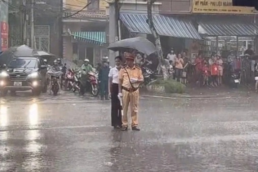 Đại úy CSGT làm nhiệm vụ A80 dưới mưa lớn được người dân che ô