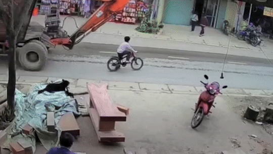 Bé trai đi xe đạp bị máy xúc tông, cuốn vào gầm