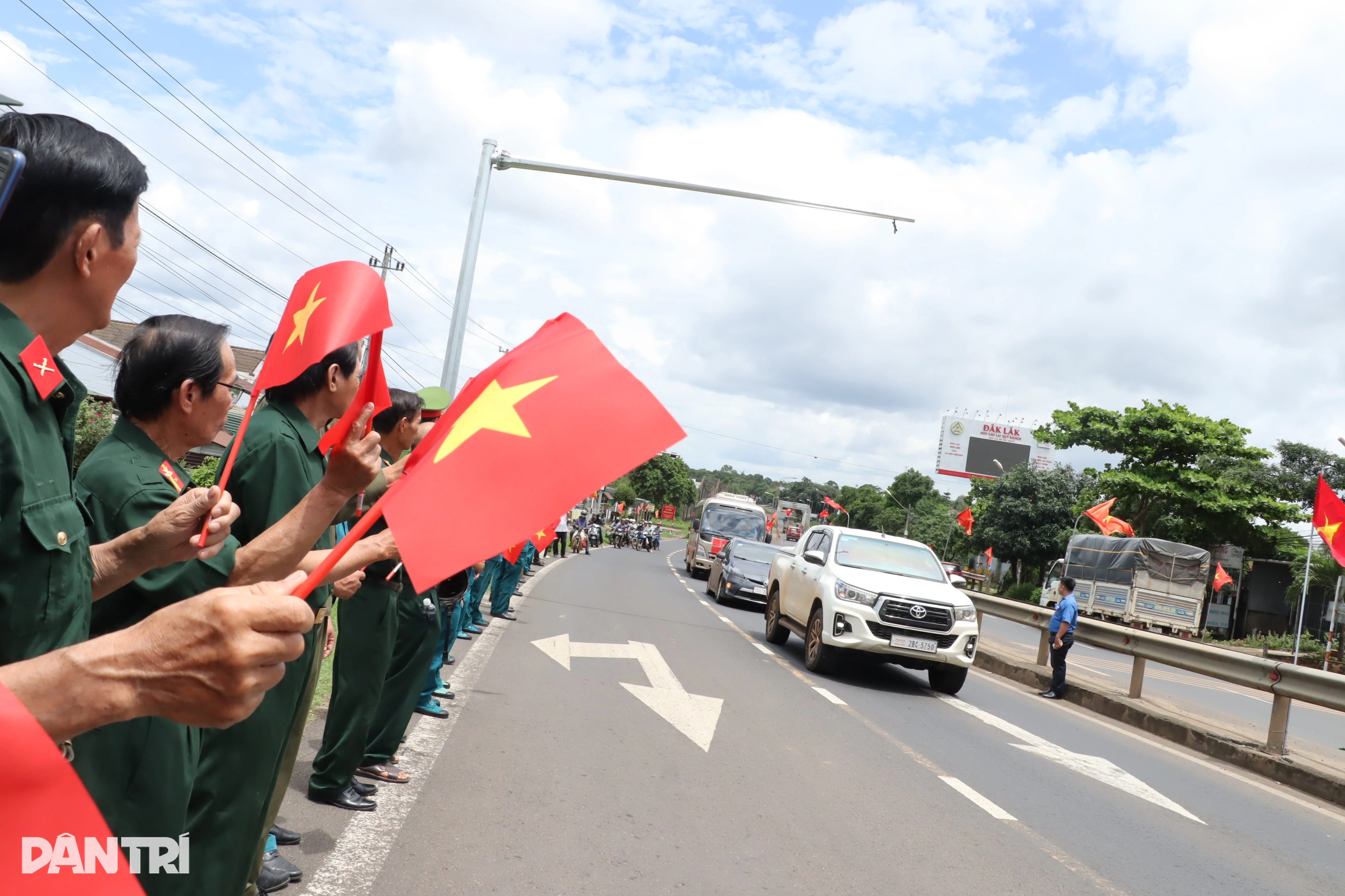 Hàng trăm người cầm cờ tổ quốc đứng bên đường đón 27 liệt sỹ hồi hương