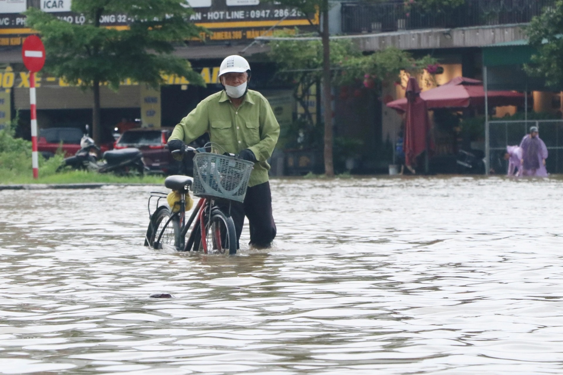 Nước ngập nửa bánh xe, người dân bì bõm trên đường sau mưa lớn