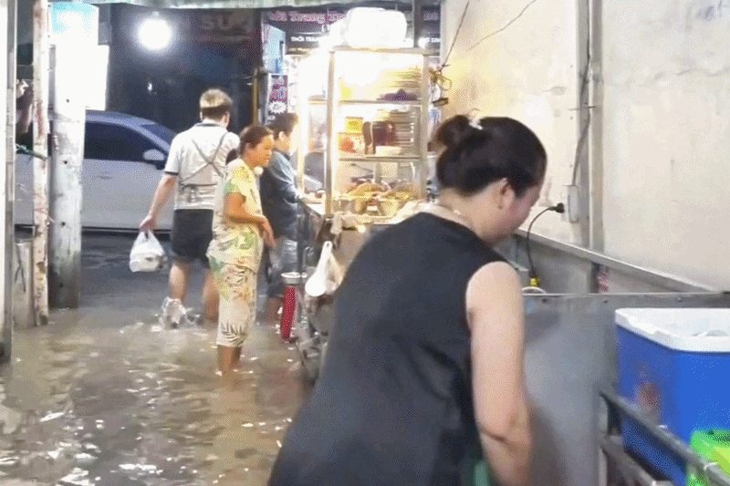 Người dân TPHCM lội nước ăn cơm tối trong mùa triều cường
