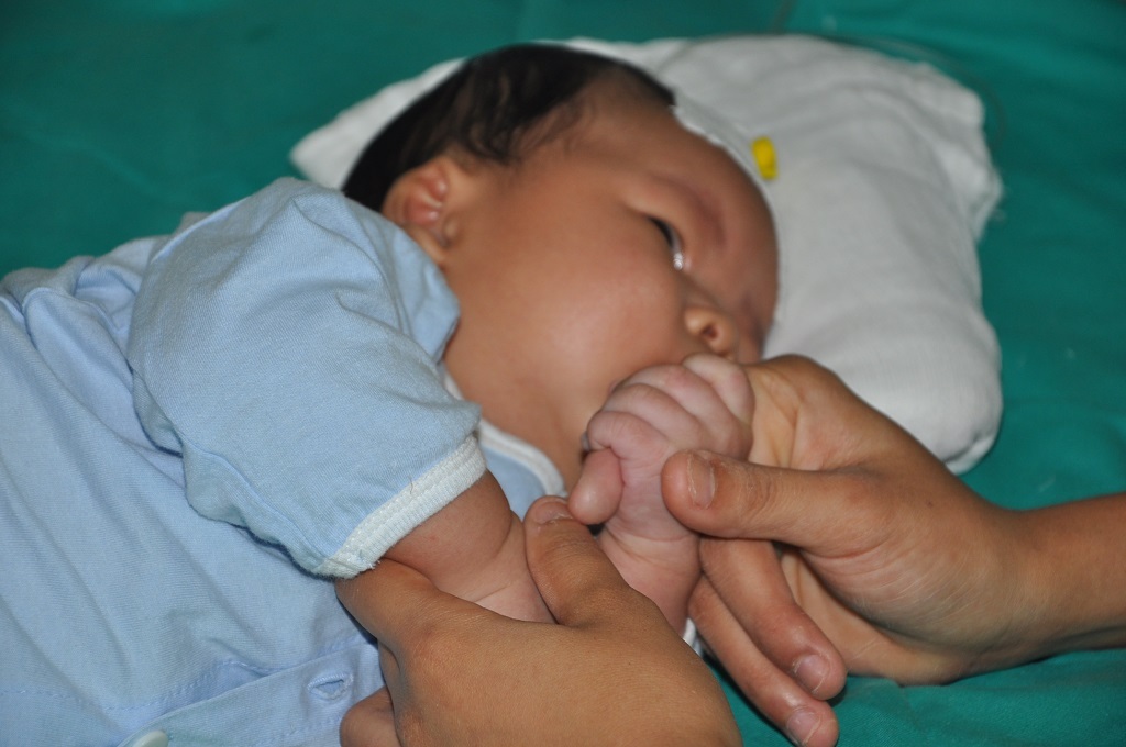 Em thèm được mẹ bế ẵm nên nắm chặt tay mẹ.