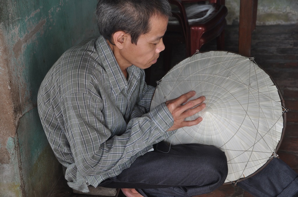 Hàng ngày anh Sơn ngồi cặm cụi khâu nón kiếm tiền cho vợ đi viện.