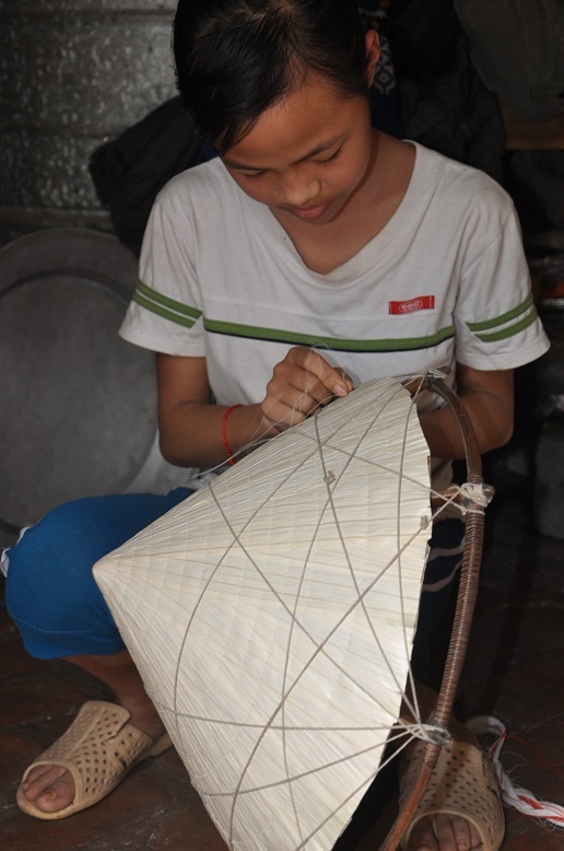 Thương mẹ, sau giờ lên lớp, bé Huân lại cặm cụi ngồi khâu nón kiếm tiền.