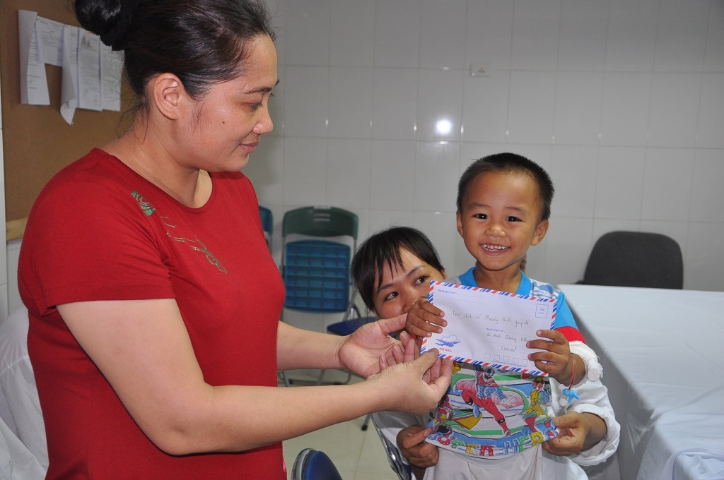 Em bé dễ thương vui mừng nhận được quà của bác Huyền cho.