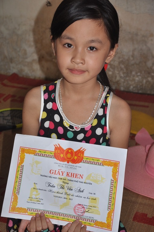 Em khoe giấy khen của mình với bà.