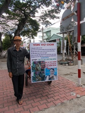 Anh Thuận bên tấm bảng thông báo tìm vợ con