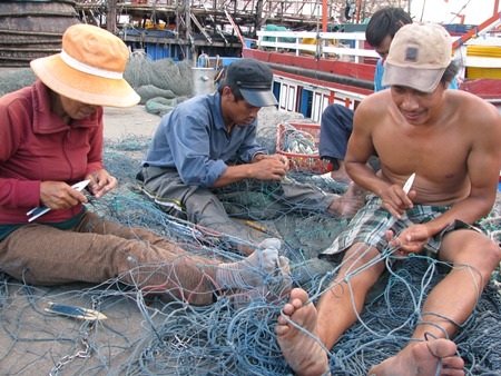 Ngư dân đang vá lại lưới chuẩn bị vươn khơi