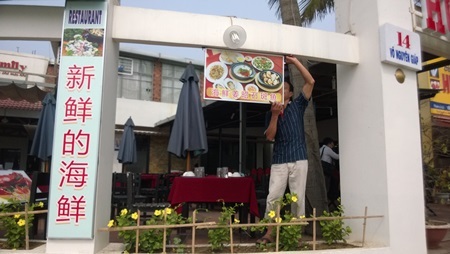 Một cơ sở kinh doanh đang chấp hành việc tháo gỡ biển hiệu sai quy định (ảnh Khánh Hồng)