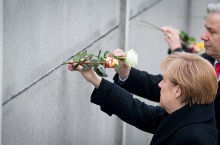 Bà Merkel gài hoa lên đoạn tường của Bức tường Berlin.