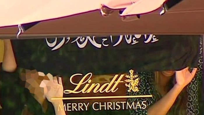 Thực hư lá cờ thánh chiến trong vụ bắt cóc con tin tại Sydney - 1 Lá cờ các con tin bị ép cầm trong quán cà phê Lindt (Ảnh SHM)