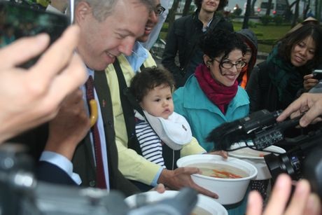 Đại sứ Ted Osius và người bạn đời bưng các chậu cá chép để chuẩn bị thả cá xuống Hồ Tây. (Ảnh: