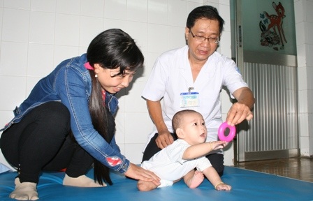 Bác sĩ hướng dẫn thân nhân tập vật lý trị liệu cho cậu bé