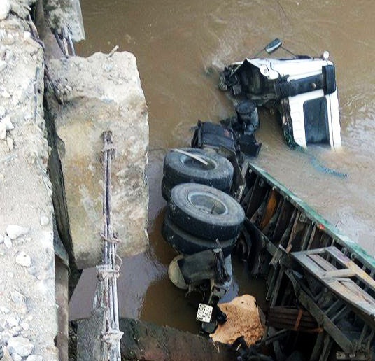 
Sau khi đâm gãy lan can cầu, chiếc xe container rơi xuống suối.
