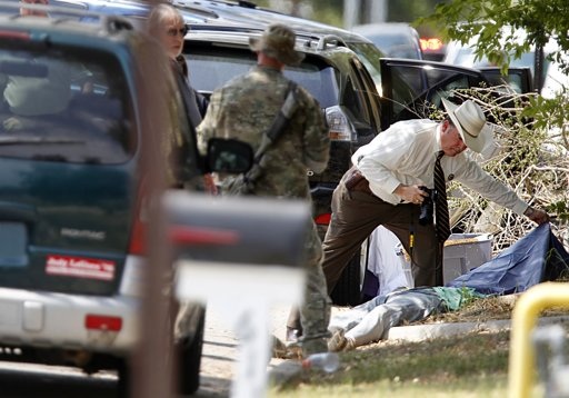 Một nhân viên điều tra đứng cạnh một thi thể tại hiện trường vụ nổ súng.