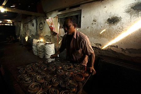 Ông Wakira đưa khay da rắn vào lò để sấy.