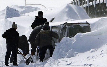 Các nhân viên cứu hộ đang đào tuyết để tiếp cận một chiếc ôtô bị mắc kẹt.