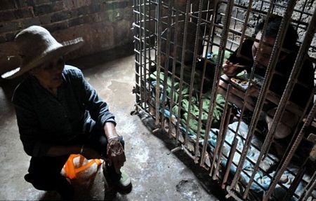 Người mẹ già ngồi nhìn còn ăn cơm trong chiếc lồng sắt kiên cố.