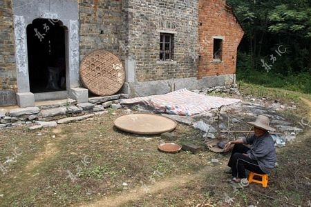 Người mẹ đau khổi ngồi trước sân ngôi nhà của gia đình ở làng Ruichang.