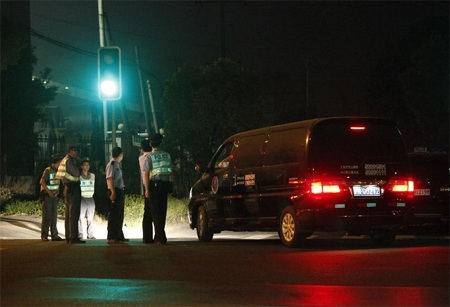 Các cảnh sát và nhân viên an ninh đứng tại cổng nhà máy, nơi xảy ra các vụ giết người.