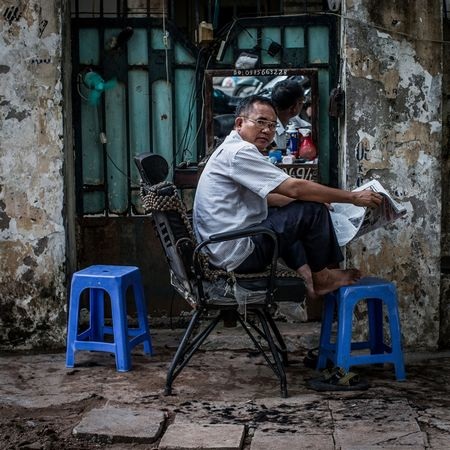 Ông Voi, 43 tuổi, đọc báo trong lúc vắng khách.