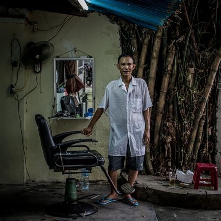 Điểm cắt tóc đơn sơ của ông Khoi, 49 tuổi, nằm cạnh một bụi tre râm mát.