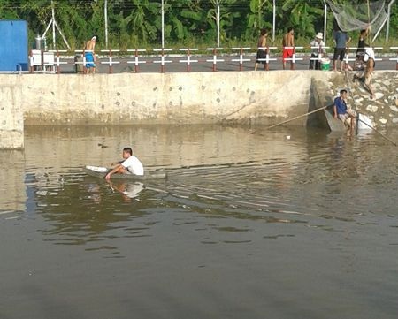 Một người đàn ông đi thuyền trên sông để rải lưới.