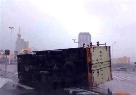 Xe tải đang lưu thông bị gió bão quật đổ xuống đường.