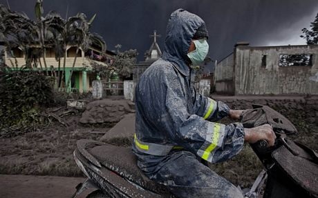 "Cơn thịnh nộ" của núi lửa Sinabung - 12 Tro bụi rơi đầy xuống quần áo và xe của một người đàn ông đang di chuyển trên đường.