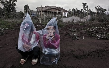 "Cơn thịnh nộ" của núi lửa Sinabung - 9 Các em nhỏ đội các núi nilon để tránh hít phải khói bụi.