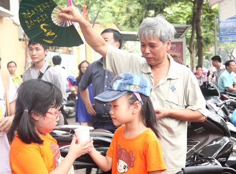 Mát lòng những cốc trà “tiếp sức mùa thi” từ các em nhỏ - 7 Một phụ huynh lớn tuổi nhường lại nước cho các em nhỏ,
và quạt mát cho các em.