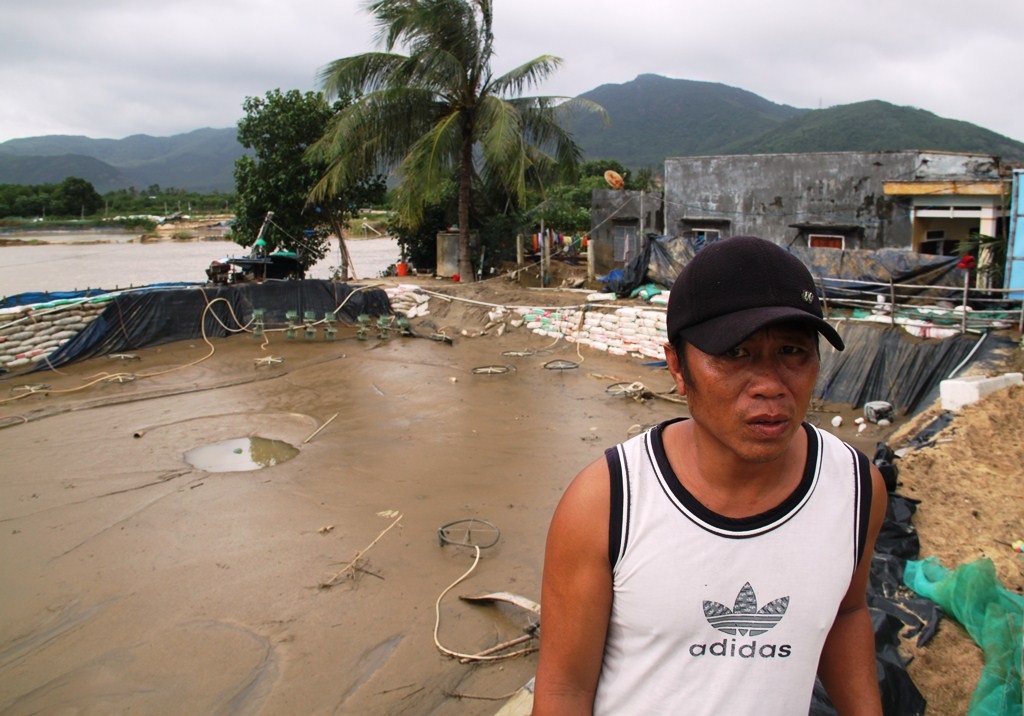 Anh Tý bên hồ tôm bị lũ đánh sạt bờ, rách bạt