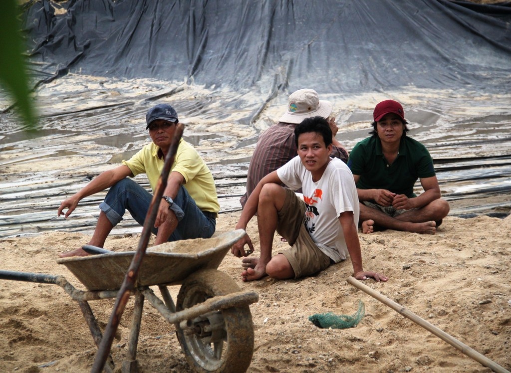 Ông Đức (áo vàng) cùng các nhân công đang xúc cát sỏi bị lũ cuốn vào 5 hồ tôm của gia đình
