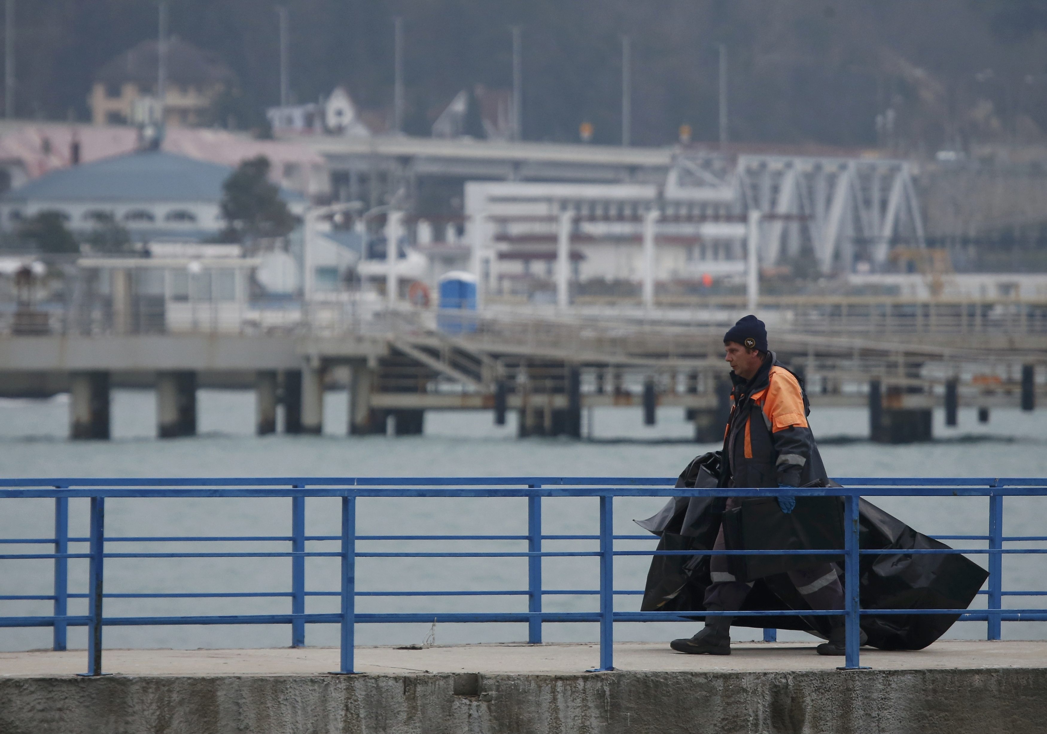 Một nhân viên cứu hộ mang túi đựng thi thể nạn nhân vụ máy bay rơi