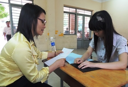 Cảm phục nghị lực của cô gái khiếm thị thi đại học - 11 Em Bùi Thị Dung điền thông tin dự thi vào theo hướng dẫn của giám thị.