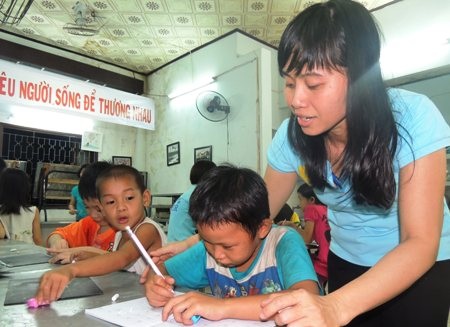 Lớp học tình thương nơi quán cơm 2.000 đồng - 3 Cô giáo Đỗ Thị Kim Dung chỉ dẫn em Lý Hoàng Kim Châu viết những nét chữ đầu đời.