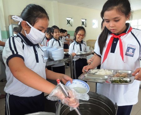 Em Vũ Ngân Anh (bên trái) tham gia công việc chia đồ ăn cho bạn.