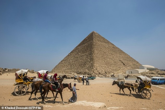 Egyptians pass by the Great Pyramid of Giza.  Two mysterious hollow spaces in the heart of the pyramid have recently been discovered.