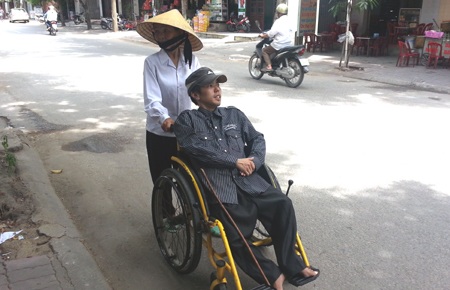 Bà Soa đẩy con trên xe lăn giữa cái nắng gắt gao thành Vinh đi tìm chỗ ăn uống.